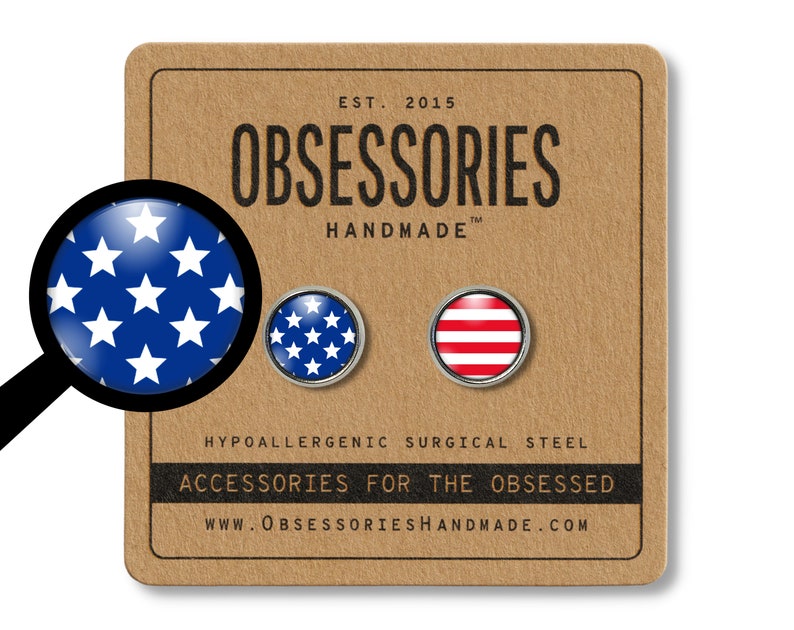 Pode incluir: Um par de brincos de press&atilde;o de a&ccedil;o cir&uacute;rgico hipoalerg&ecirc;nico com um design listrado vermelho e branco e um design de estrelas azuis e brancas. Os brincos s&atilde;o exibidos em um cart&atilde;o marrom com o texto "OBSESSORIES HANDMADE" e "ACCESSORIES FOR THE OBSESSED".