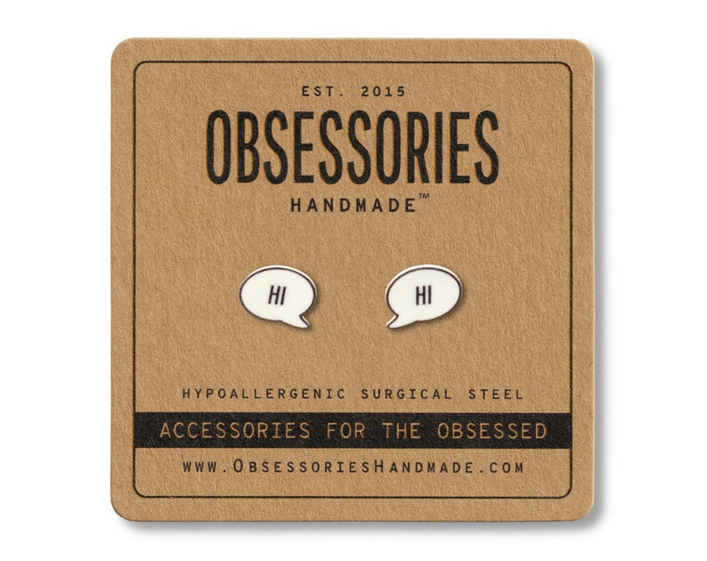 May include: A pair of white and black speech bubble earrings with the word "HI" inside, displayed on a brown card. The card features the brand name "OBSESSORIES HANDMADE" and the text "ACCESSORIES FOR THE OBSESSED".
