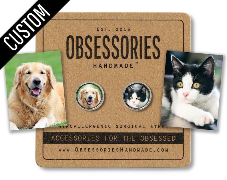 May include: A set of two custom pet portrait pinback buttons. The buttons are made of hypoallergenic surgical steel and feature a golden retriever and a black and white cat. The buttons are displayed on a brown card with the text "OBSESSORIES HANDMADE" and "ACCESSORIES FOR THE OBSESSED".