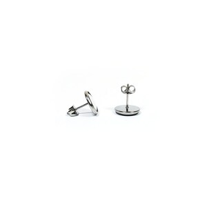 May include: A pair of silver stud earrings with a round, flat design. The earrings have a post and butterfly back.