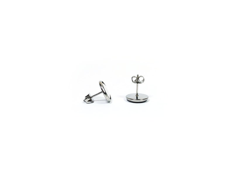 May include: A pair of silver stud earrings with a round, flat design. The earrings have a post and butterfly back.