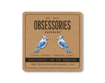 Könnte beinhalten: Ohrringe mit Blaumeisen-Motiv auf einer braunen Karte. Die Ohrringe sind blau, weiß und schwarz. Die Karte trägt die Aufschrift "OBSESSORIES HANDMADE" und "ACCESSORIES FOR THE OBSESSED". Aus hypoallergenem Chirurgenstahl.