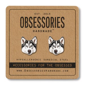 May include: A pair of hypoallergenic surgical steel stud earrings featuring a detailed illustration of a husky dog's face. The earrings are displayed on a brown card with the text "OBSESSORIES HANDMADE" and "ACCESSORIES FOR THE OBSESSED".