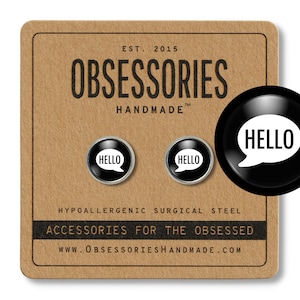 May include: A pair of black and white enamel pin earrings with the word "HELLO" in a speech bubble. The earrings are on a brown background with the text "OBSESSORIES HANDMADE" and "ACCESSORIES FOR THE OBSESSED".