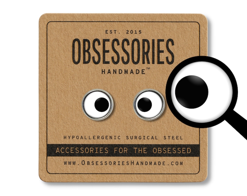 May include: A pair of small, white, round earrings with black centers. The earrings are on a brown card with the text "OBSESSORIES HANDMADE" and "ACCESSORIES FOR THE OBSESSED".