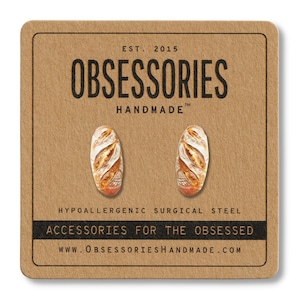 Może przedstawiać: Kolczyki sztyfty w kształcie miniaturowych bagietek, prezentowane na brązowej karcie. Karta zawiera tekst "OBSESSORIES HANDMADE" i "ACCESSORIES FOR THE OBSESSED". Kolczyki wykonane są z hipoalergicznej stali chirurgicznej.