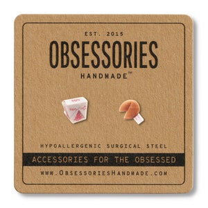 May include: A pair of novelty earrings on a brown card. One earring is a white and pink takeout container, the other is a fortune cookie with a white fortune. The card reads "OBSESSORIES HANDMADE" and "ACCESSORIES FOR THE OBSESSED."