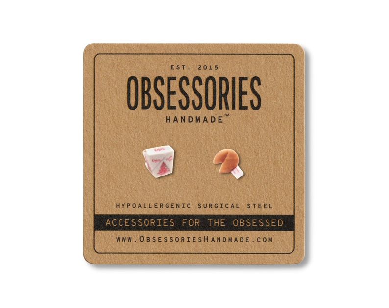 May include: A pair of stud earrings on a brown card. One earring is a miniature Chinese takeout box, the other is a fortune cookie. The card reads "OBSESSORIES HANDMADE" and "ACCESSORIES FOR THE OBSESSED."