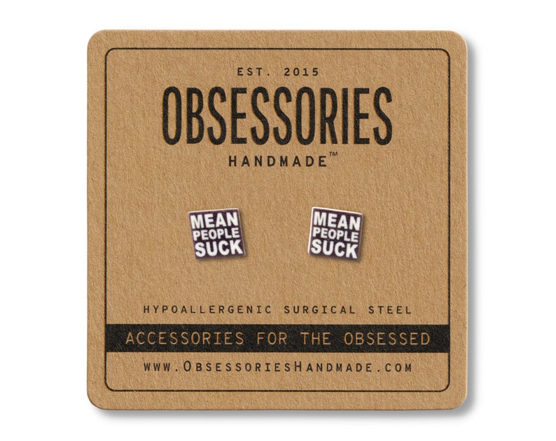 Op de afbeelding: Een paar vierkante oorbellen met de tekst "MEAN PEOPLE SUCK" op een bruine kaart. De kaart toont ook de merknaam "OBSESSORIES HANDMADE" en de tekst "ACCESSORIES FOR THE OBSESSED". De oorbellen zijn gemaakt van hypoallergeen chirurgisch staal.