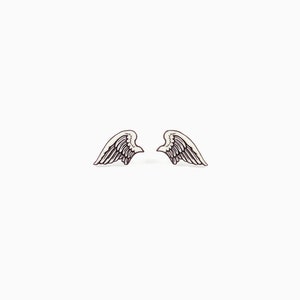 Puede incluir: Un par de pendientes peque&ntilde;os con forma de alas, blancos y negros. Cada ala tiene un dise&ntilde;o detallado de plumas. Los pendientes son sim&eacute;tricos y se presentan sobre un fondo blanco liso, resaltando su delicado dise&ntilde;o.