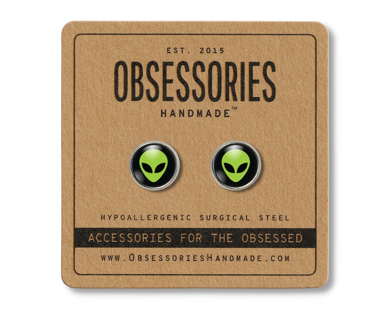 May include: A pair of green alien face stud earrings on a brown card with the text "OBSESSORIES HANDMADE" and "ACCESSORIES FOR THE OBSESSED".