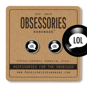 May include: A pair of black and silver earrings with a white speech bubble that says "LOL". The earrings are on a brown background with the text "OBSESSORIES HANDMADE" and "HYPOALLERGENIC SURGICAL STEEL ACCESSORIES FOR THE OBSESSED WWW.OBSESSORIESHANDMADE.COM".