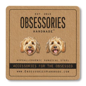 Pu&ograve; includere: Una scheda quadrata marrone con il testo "OBSESSORIES HANDMADE" e due illustrazioni di facce di cane. La scheda include anche il testo "EST. 2015", "HYPOALLERGENIC SURGICAL STEEL", "ACCESSORIES FOR THE OBSESSED" e un indirizzo web.