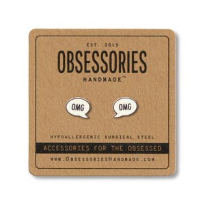 May include: A pair of white speech bubble earrings with the word "OMG" in black lettering, displayed on a brown card. The card features the text "OBSESSORIES HANDMADE" and "ACCESSORIES FOR THE OBSESSED".