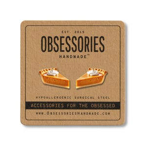 May include: A square, brown card with the text "OBSESSORIES HANDMADE" and two pumpkin pie slice earrings. The card also includes the text "ACCESSORIES FOR THE OBSESSED" and "WWW.OBSESSORIESHANDMADE.COM".