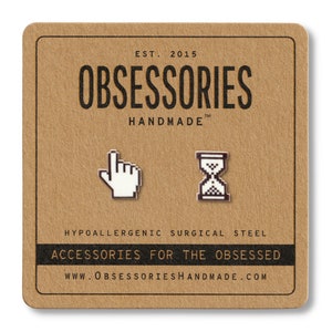 Pode incluir: Um cartão castanho com o texto "EST. 2015 OBSESSORIES HANDMADE" e o texto "HYPOALLERGENIC SURGICAL STEEL ACCESSORIES FOR THE OBSESSED WWW.OBSESSORIESHANDMADE.COM". O cartão tem dois pequenos pinos prateados nele, um é um cursor pixelado e o outro é um relógio de areia pixelado.