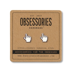 May include: A pair of white cursor-shaped earrings on a brown card. The card has the text "OBSESSORIES HANDMADE" and "ACCESSORIES FOR THE OBSESSED". The earrings are made of hypoallergenic surgical steel.
