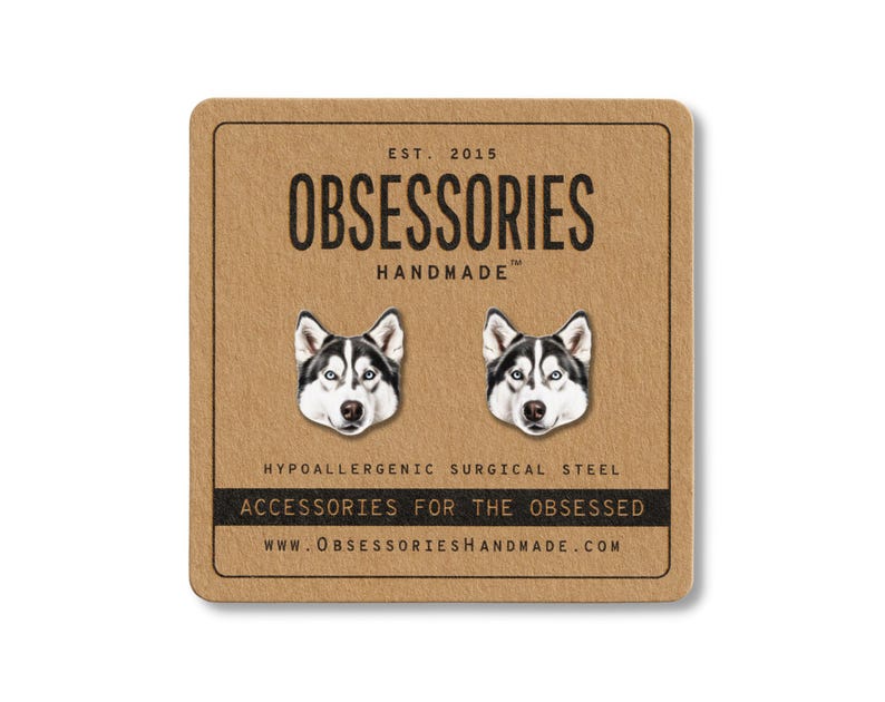 May include: A pair of silver-colored husky dog stud earrings on a brown card. The card reads "OBSESSORIES HANDMADE" and "ACCESSORIES FOR THE OBSESSED". The earrings are made of hypoallergenic surgical steel.