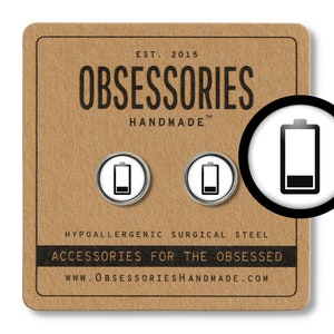 May include: Two silver-colored, round, hypoallergenic surgical steel earrings with a white background and a black battery icon. The earrings are displayed on a brown card with the text "OBSESSORIES HANDMADE" and "ACCESSORIES FOR THE OBSESSED".