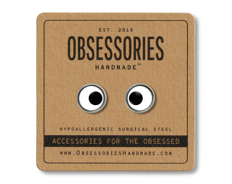 May include: A pair of silver-colored earrings with white and black googly eyes. The earrings are hypoallergenic and made of surgical steel. The card reads "OBSESSORIES HANDMADE" and "ACCESSORIES FOR THE OBSESSED".
