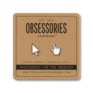 May include: A pair of silver-colored cursor and hand-shaped earrings on a brown card. The card reads "OBSESSORIES HANDMADE" and "ACCESSORIES FOR THE OBSESSED". The earrings are made of hypoallergenic surgical steel.