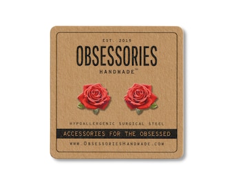 May include: A square, brown card with the text "OBSESSORIES HANDMADE" and two red rose stud earrings. The card also includes the text "ACCESSORIES FOR THE OBSESSED" and "HYPOALLERGENIC SURGICAL STEEL".