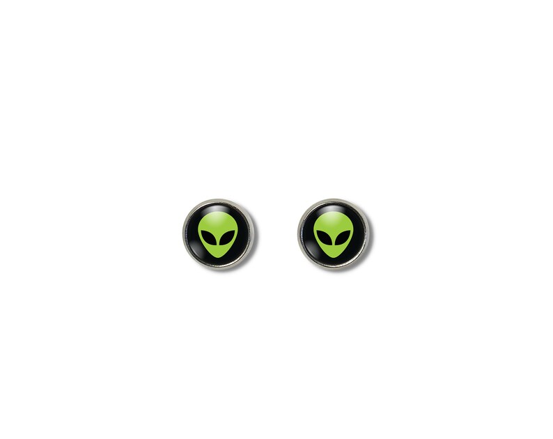 May include: A pair of silver stud earrings with black circular bases and green alien head designs.