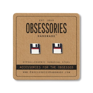 Könnte beinhalten: Quadratische Ohrstecker mit einem Disketten-Design, präsentiert auf einer braunen Karte. Die Ohrringe haben ein schwarz-weiß-rotes Farbschema. Auf der Karte steht "OBSESSORIES HANDMADE" und "ACCESSORIES FOR THE OBSESSED".