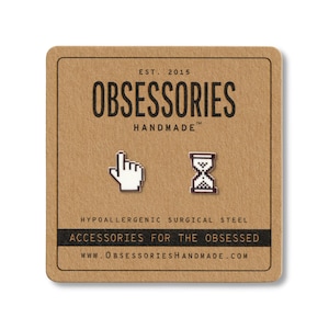 May include: A pair of silver-colored stud earrings on a brown card. One earring is a white hand cursor, the other is an hourglass. The card reads "OBSESSORIES HANDMADE" and "ACCESSORIES FOR THE OBSESSED".
