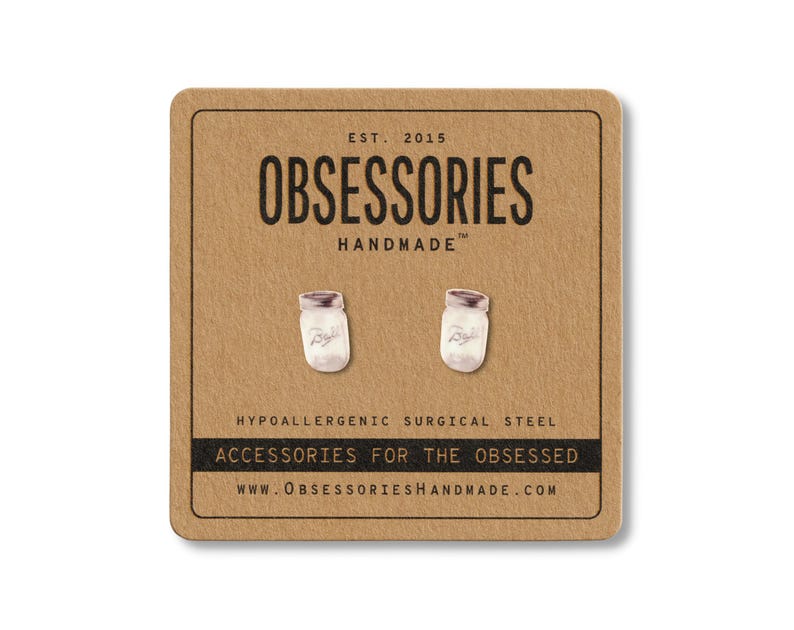 May include: A pair of mason jar stud earrings on a brown card. The card has the text "OBSESSORIES HANDMADE" and "ACCESSORIES FOR THE OBSESSED". The earrings are made of hypoallergenic surgical steel.