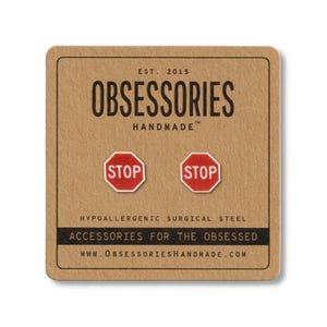 May include: A pair of red and white stop sign stud earrings on a brown card. The card has the text "OBSESSORIES HANDMADE" and "ACCESSORIES FOR THE OBSESSED". The earrings are made of hypoallergenic surgical steel.