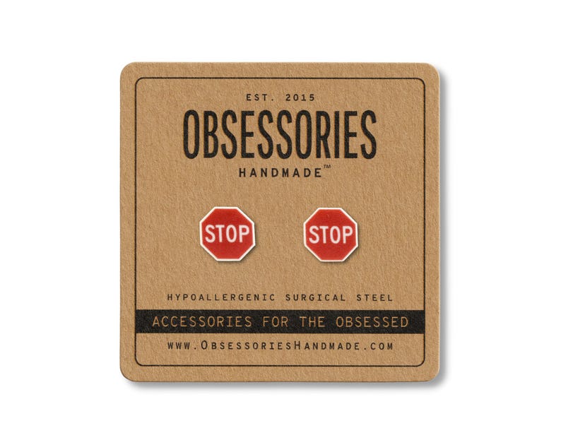 May include: A pair of red and white stop sign stud earrings on a brown card. The card has the text "OBSESSORIES HANDMADE" and "ACCESSORIES FOR THE OBSESSED". The earrings are made of hypoallergenic surgical steel.