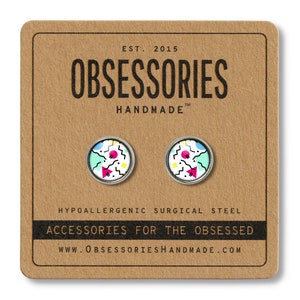 K&ouml;nnte beinhalten: Ein Paar silberne Ohrstecker mit einem geometrischen Design in Pink, Blau, Gelb und Wei&szlig; auf einer braunen Karte mit dem Text "OBSESSORIES HANDMADE" und "ACCESSORIES FOR THE OBSESSED".