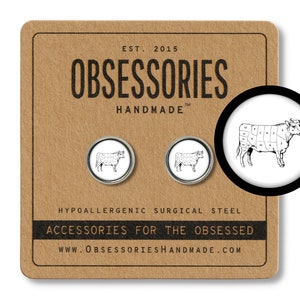 May include: A pair of silver cufflinks with a black and white illustration of a cow divided into sections, labeled with different cuts of meat. The cufflinks are on a brown background with the text "OBSESSORIES HANDMADE" and "ACCESSORIES FOR THE OBSESSED".