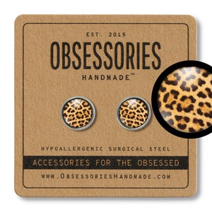 May include: A pair of hypoallergenic surgical steel earrings with a leopard print design. The earrings are round and have a silver backing. The text "OBSESSORIES HANDMADE" is printed on the card.