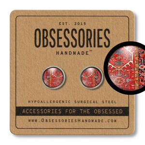 K&ouml;nnte beinhalten: Ein Paar Ohrstecker mit einem roten, blauen und wei&szlig;en Muster, das an einen traditionellen Teppich erinnert. Die Ohrringe sind aus hypoallergenem Chirurgenstahl gefertigt und mit "OBSESSORIES HANDMADE" gekennzeichnet.