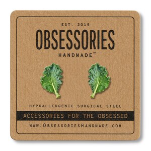 May include: A pair of green kale leaf earrings on a brown card. The card has the text "OBSESSORIES HANDMADE" and "ACCESSORIES FOR THE OBSESSED". The earrings are made of hypoallergenic surgical steel.