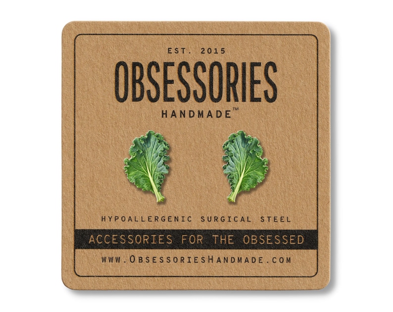 May include: A pair of green kale leaf earrings on a brown card. The card has the text "OBSESSORIES HANDMADE" and "ACCESSORIES FOR THE OBSESSED". The earrings are made of hypoallergenic surgical steel.