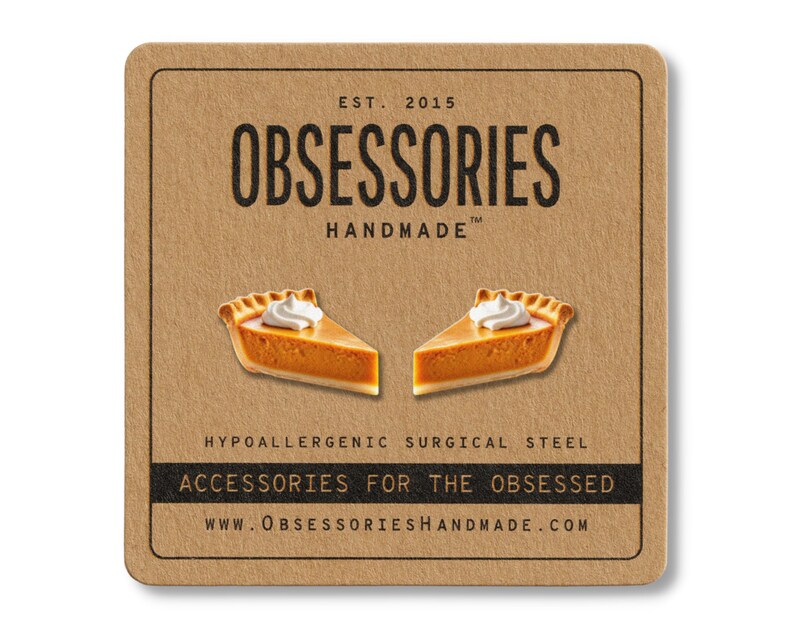 May include: A square, brown card features the text "OBSESSORIES HANDMADE" and two pumpkin pie slice earrings. The earrings have orange filling and white whipped cream. The card also states "ACCESSORIES FOR THE OBSESSED" and "HYPOALLERGENIC SURGICAL STEEL."