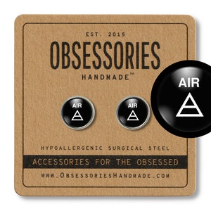May include: A pair of black and silver stud earrings featuring a white triangle and the word "AIR" on each earring. The earrings are displayed on a brown background with the text "OBSESSORIES HANDMADE" and "HYPOALLERGENIC SURGICAL STEEL ACCESSORIES FOR THE OBSESSED WWW.OBSESSORIESHANDMADE.COM".