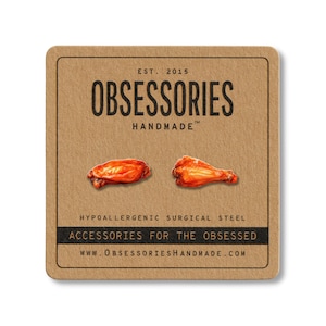Puede incluir: Una tarjeta cuadrada marr&oacute;n con el texto "OBSESSORIES HANDMADE" y dos ilustraciones de alitas de pollo. La tarjeta tambi&eacute;n incluye el texto "ACCESSORIES FOR THE OBSESSED" y "WWW.OBSESSORIESHANDMADE.COM".