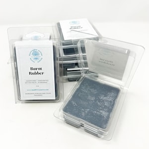 May include: Several packages of soy wax melts in clear plastic containers. Each package contains a dark gray wax melt labeled "Burnt Rubber." The packaging includes the text "Handpoured Soy Wax Melts in Arkansas."