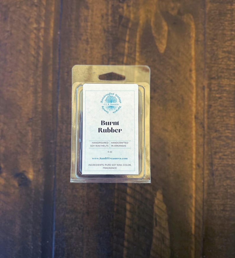 May include: A clear plastic package containing soy wax melts. The label reads "Burnt Rubber" and lists ingredients. The product is hand-poured in Arkansas and weighs 4 oz.