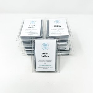 May include: Stacked clear plastic containers holding soy wax melts. Each container has a white label with the text "Burnt Rubber". The labels also include the words "Handpoured, Handcrafted Soy Wax Melts in Arkansas".