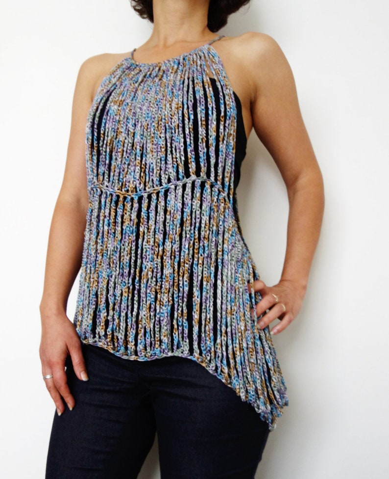 May include: A crocheted halter top with a fringe design in shades of blue, brown, and purple. The top is asymmetrical and has a loose fit.