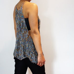 May include: A crocheted top with a multicolored, beaded design. The top has a loose, flowing fit and a scoop neck.