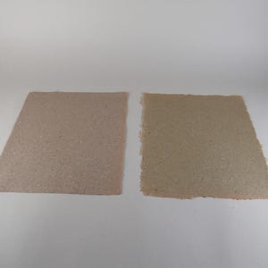 May include: Two handmade paper sheets in shades of brown and tan. The sheet on the left has a clean, angled edge, while the sheet on the right has a rough, torn edge. Both have a speckled texture.