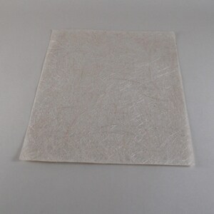 May include: A rectangular, off-white sheet with a fibrous texture. The material appears to be a composite, with visible strands creating a subtle, irregular pattern across the surface. The sheet is set against a neutral background.