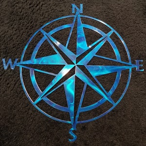 May include: A blue metal compass with a star-shaped design and the cardinal directions N, S, E, and W.