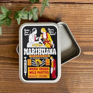 May include: A rectangular silver metal tin featuring a vintage-style graphic print with the text MARIHUANA, Daring Drug Expose, Horror Shame Despair, Weed With Roots In Hell, Not Recommended For Children, Misery, Weird Orgies Wild Parties Unleashed Passions.